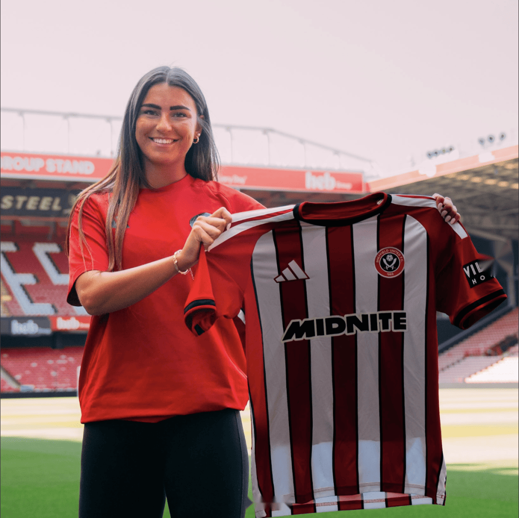 Reliance-represented player holding up a signed club shirt at the stadium