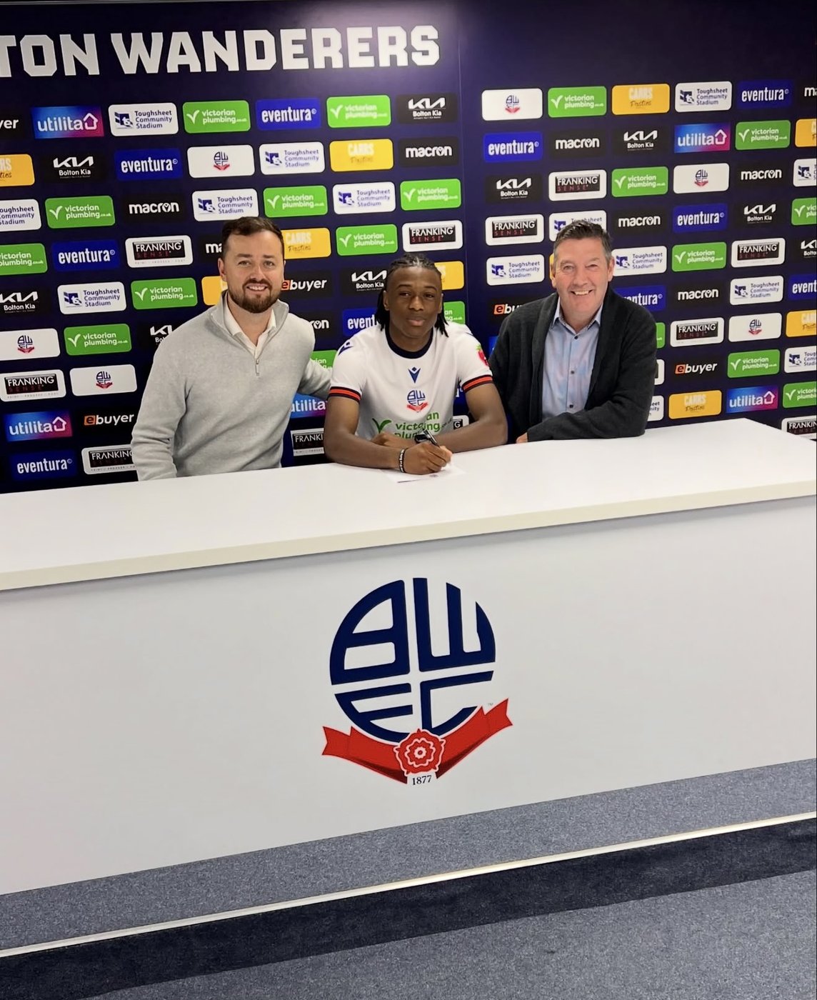 Reliance Talent client signing a contract at Bolton Wanderers, flanked by two representatives